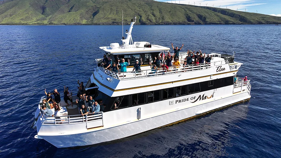 Aerial view of Pride of Maui Elua boat during Maui Food Bank recognition cruise with volunteers visible on deck and Maui coastline in background