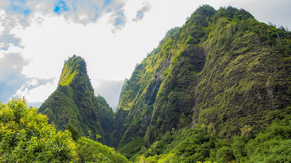 Sunlight filtering through dramatic ridges in ʻĪao Valley.