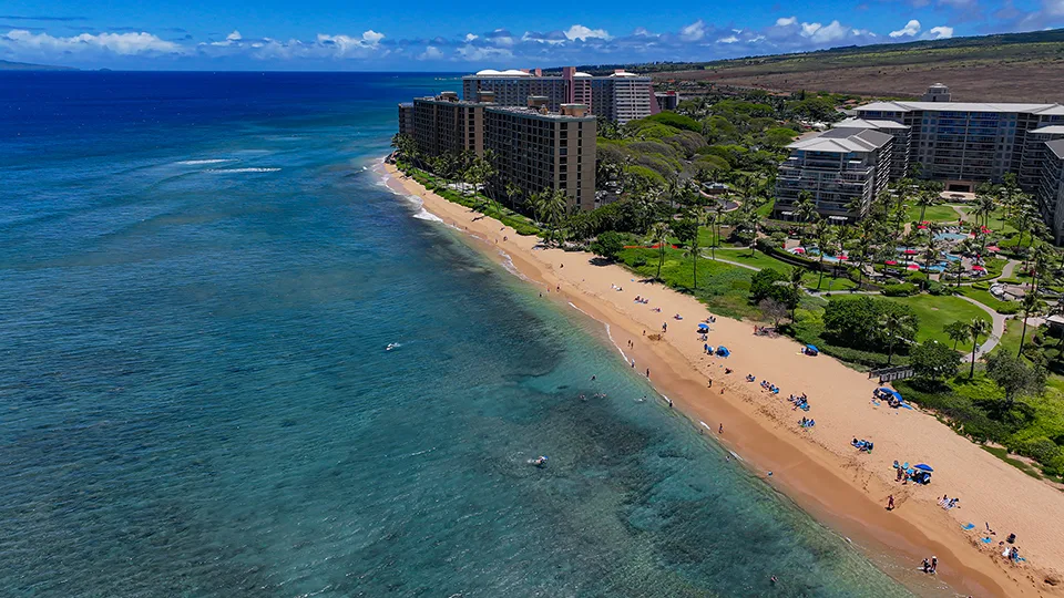 Aerial view of Kāʻanapali Beach lined with resorts and turquoise water.