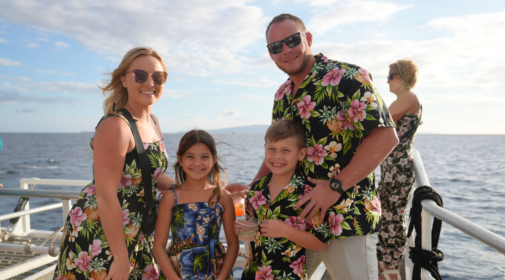 Family wearing aloha attire smiling aboard the Pride of Maui Sunset Dinner Cruise