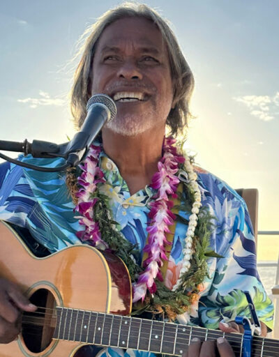 Musician Kekoa performing Hawaiian songs on guitar during the Pride of Maui Sunset Dinner Cruise