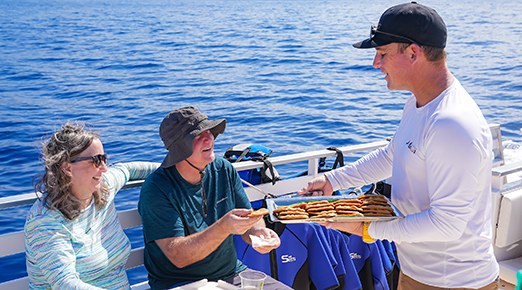 Captain serving fresh cookies to guests on ‘Elua’s deck