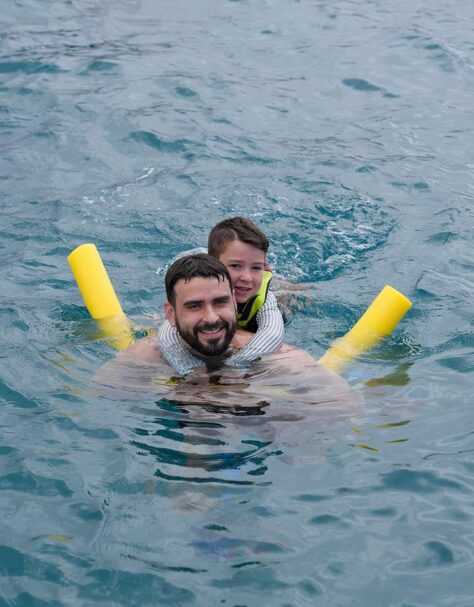 Parent and child floating with noodles during a snorkel stop off Maui.