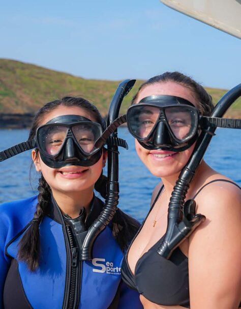 Two snorkelers on deck aboard Pride of Maui with Molokini in the background.